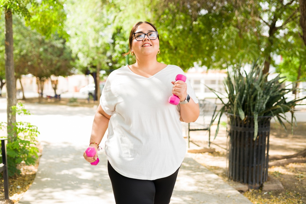 Woman walking outdoors with dumbbells, weight loss injections guide Ireland